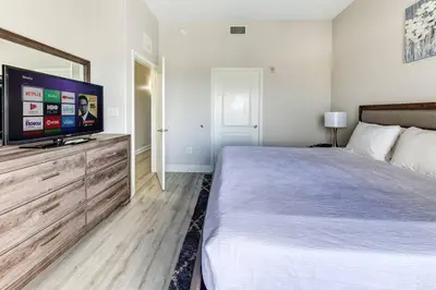 a bedroom with a large bed and a flat screen tv at Disney Lakefront Luxury! in Orlando
