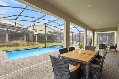 a patio with a table and chairs and a swimming pool at 4561 Majestic 9BD Kingdom Retreat Near Disney in Kissimmee