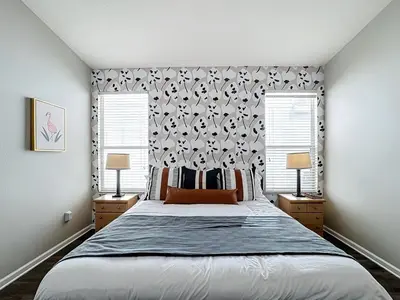 a bedroom with a large bed and two windows at Windsor Palms Minion, Princess, Mickey, Pool Home in Kissimmee