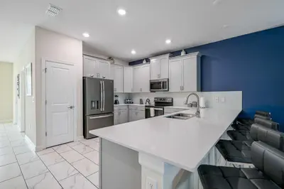 a kitchen with white cabinets and a blue wall at Storey Lake Resort 1136 - Hosted by Top Villas in Kissimmee