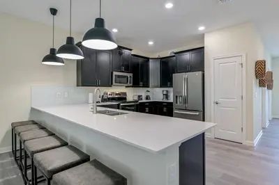 a kitchen with a large white counter and black cabinets at Storey Lake Resort 1120 - Hosted by Top Villas in Kissimmee