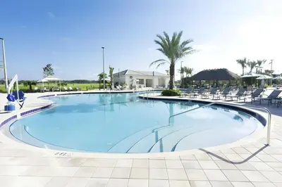 a swimming pool at a resort with chairs and palm trees at Beautiful 5bed home with Free Resort Access 4817 in Kissimmee