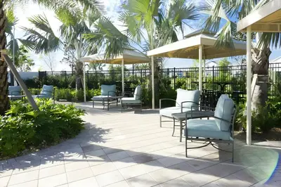a patio with chairs and umbrellas and palm trees at Beautiful 5bed home with Free Resort Access 4817 in Kissimmee