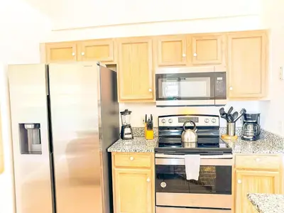 a kitchen with wooden cabinets and a stainless steel refrigerator at LB4701PL - 4 Beds villa - with pool and game room in Kissimmee