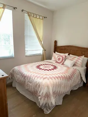 a bedroom with a bed with a comforter and two windows at Magical Home with private pool and close to parks in Kissimmee