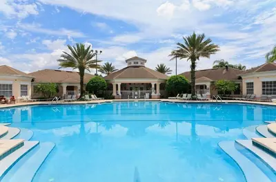 a large swimming pool with palm trees and a building at Magical Home with private pool and close to parks in Kissimmee