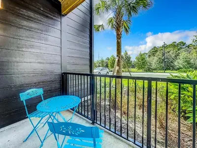 a balcony with two chairs and a table and a palm tree at Luxury Apartments Near Disney in Orlando