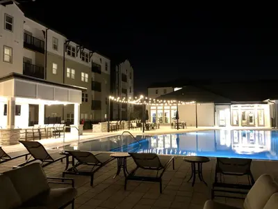 a swimming pool with chairs and tables at night at Luxury Apartments Near Disney in Orlando