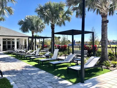 a row of chaise lounges on the grass with palm trees at Luxury Apartments Near Disney in Orlando