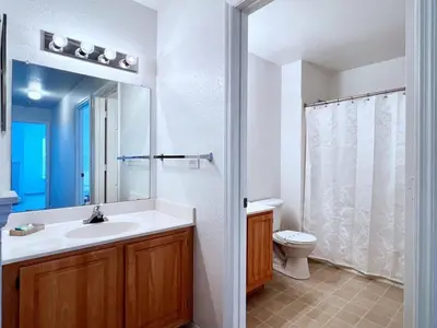 a bathroom with a sink and a toilet and a mirror at Cute and Cozy 4Bed Townhome Venetian Bay-2200SCD in Kissimmee