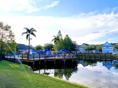 a dock with tables and blue umbrellas next to a river at Cute and Cozy 4Bed Townhome Venetian Bay-2200SCD in Kissimmee