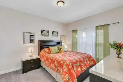 a bedroom with a bed with a orange bedspread at Waterpark Disney wPoolLakeView Storey Lake in Kissimmee
