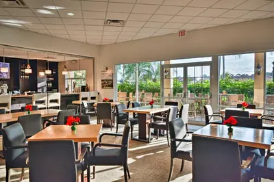 a restaurant with tables and chairs and windows at 4 Mi to Disney World Townhome with Hot Tub and Lanai! in Kissimmee