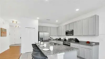 a kitchen with white cabinets and a large counter top at Disney Area Retreat 6BR4BA with Private Pool Theater Game Room Bella Vida Resort BV4509 in Kissimmee