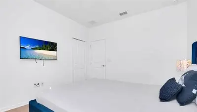 a white bedroom with a bed and a tv on the wall at Disney Area Retreat 6BR4BA with Private Pool Theater Game Room Bella Vida Resort BV4509 in Kissimmee