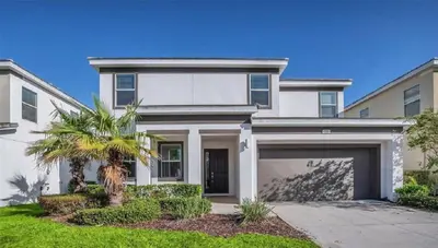 a white house with a palm tree and a garage at Disney Area Retreat 6BR4BA with Private Pool Theater Game Room Bella Vida Resort BV4509 in Kissimmee