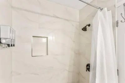 a bathroom with a shower with a white shower curtain at King bd Charming 2-Storey Cottage w PrivateYard in Orlando
