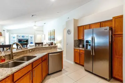 a kitchen with a stainless steel refrigerator and wooden cabinets at Beautiful 4 Bed Villa With Southwest Facing Pool in Orlando