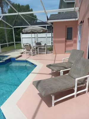 a pair of chairs and an umbrella next to a swimming pool at Fabulous 4 Bed South Facing Lake View Near Disney in Orlando