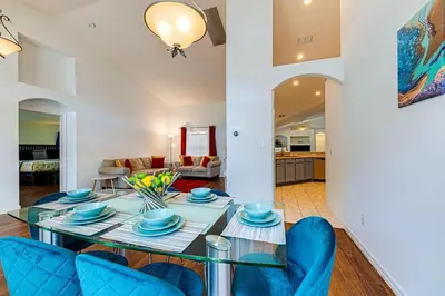 a living room with a table and blue chairs at Spacious 4 Bed South Facing Pool Villa Near Disney in Orlando