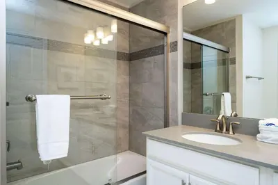 a bathroom with a shower with a sink and a mirror at Storey Lake Home Mickey & Minions Beds Sleeps 12 in Kissimmee