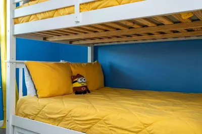 a yellow bed in a room with a bunk bed at Storey Lake Home Mickey & Minions Beds Sleeps 12 in Kissimmee