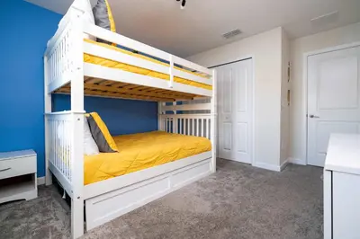 a bedroom with a bunk bed with yellow sheets at Storey Lake Home Mickey & Minions Beds Sleeps 12 in Kissimmee