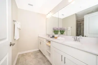 a white bathroom with a sink and a mirror at Elegant 2Bed Condo in Storey Lake Prime Location in Kissimmee
