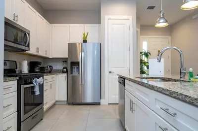 a kitchen with white cabinets and a stainless steel refrigerator at Modern Chic Home Mickey and Toy Story Rooms in Orlando