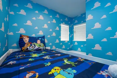 a childs bedroom with blue walls and a dinosaur themed bed at Modern Chic Home Mickey and Toy Story Rooms in Orlando