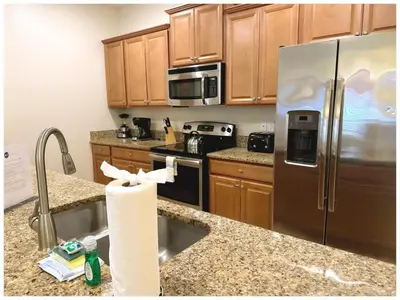 a kitchen with wooden cabinets and a stainless steel refrigerator at Home 4Bed in Storey Lake with Private Pool in Kissimmee