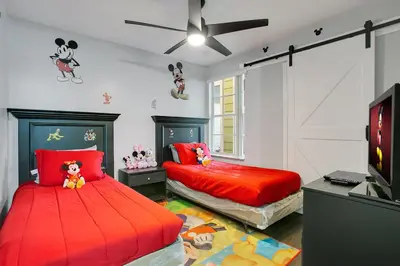 a bedroom with two beds with red sheets and a tv at Familiar Retreat with Resort Access Near Disney in Kissimmee