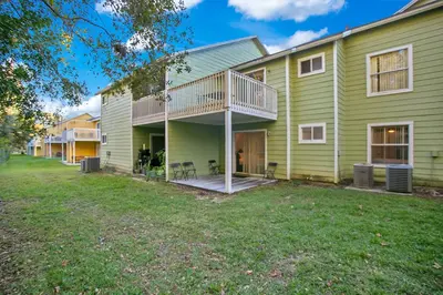 a large green house with a deck and yard at Familiar Retreat with Resort Access Near Disney in Kissimmee