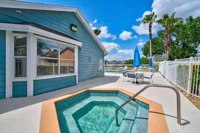 a swimming pool in front of a blue house at Familiar Retreat with Resort Access Near Disney in Kissimmee