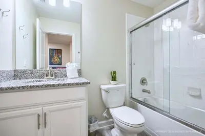 a white bathroom with a toilet and a shower at Chic Home Themed Bedrooms Game Room Best Spot in Kissimmee