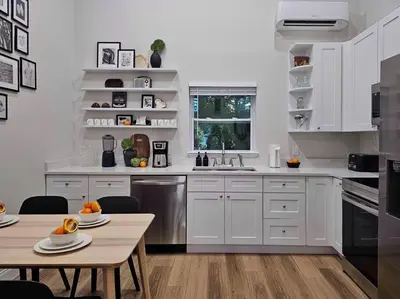 a kitchen with white cabinets and a wooden table at The Catherine - 1 mile to downtown - 2 King beds - Sleeps 5 in Orlando