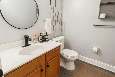 a bathroom with a sink and a toilet and a mirror at Disney-Area 3BR Townhome | Sleeps 9 | Pool + Gym in Kissimmee