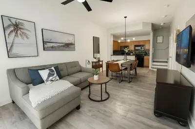 a living room with a couch and a dining room at Disney-Area 3BR Townhome | Sleeps 9 | Pool + Gym in Kissimmee