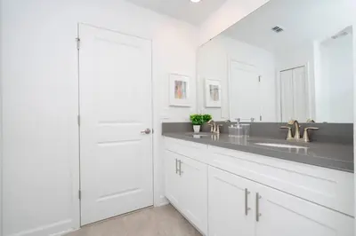 a white bathroom with a sink and a mirror at The Ultimate 9bd Disney Getaway Storey Lake in Kissimmee
