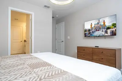 a bedroom with a large bed and a flat screen tv at The Ultimate 9bd Disney Getaway Storey Lake in Kissimmee