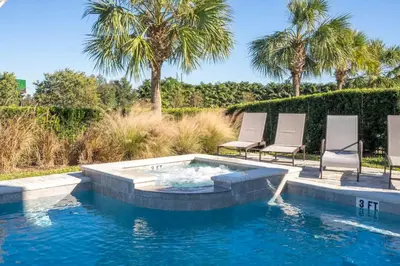 a swimming pool with two lawn chairs and a hot tub at Fantastic Disney Vacation W Pool and Movie Theater in Orlando