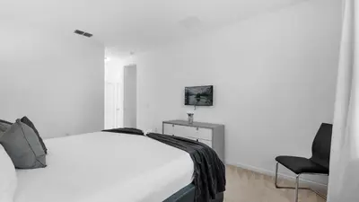 a white bedroom with a bed and a chair at Summer Getaway in FL - 6BR Home with Private Pool! in Kissimmee