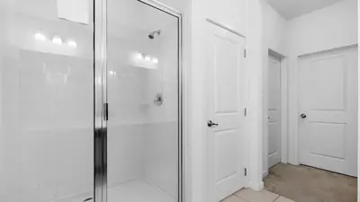 a bathroom with a glass shower and two white doors at Summer Getaway in FL - 6BR Home with Private Pool! in Kissimmee