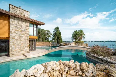 a swimming pool in front of a house at Luxury Lakefront 100,000 Gal Pool Villa - Orlando in Orlando