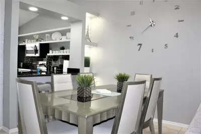 a dining room table and chairs with a clock on the wall at Wonderful Villa with swimming pool, near Orlando attractions in Kissimmee