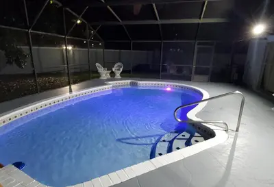 a swimming pool at night with a chair around it at Wonderful Villa with swimming pool, near Orlando attractions in Kissimmee