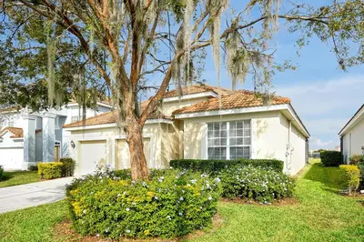 a white house with a tree in a yard at Personally Designed Home w/ Pool, Game Room near Disney in Orlando