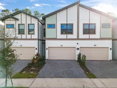 a house with two garage doors in a driveway at Lux 5BR Home, Game Room, 4 Suites & Private Pool in Orlando
