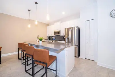 a kitchen with a bar with chairs and a refrigerator at 2585LA TOWNHOUSE 4 BEDROOMS & 3 BATHROOMS + POOL in Kissimmee