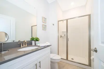 a white bathroom with a shower and a toilet at 2585LA TOWNHOUSE 4 BEDROOMS & 3 BATHROOMS + POOL in Kissimmee